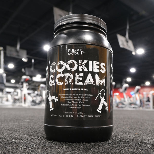 A Cookies & Cream whey protein canister up close with the blurred-out background of a gym.